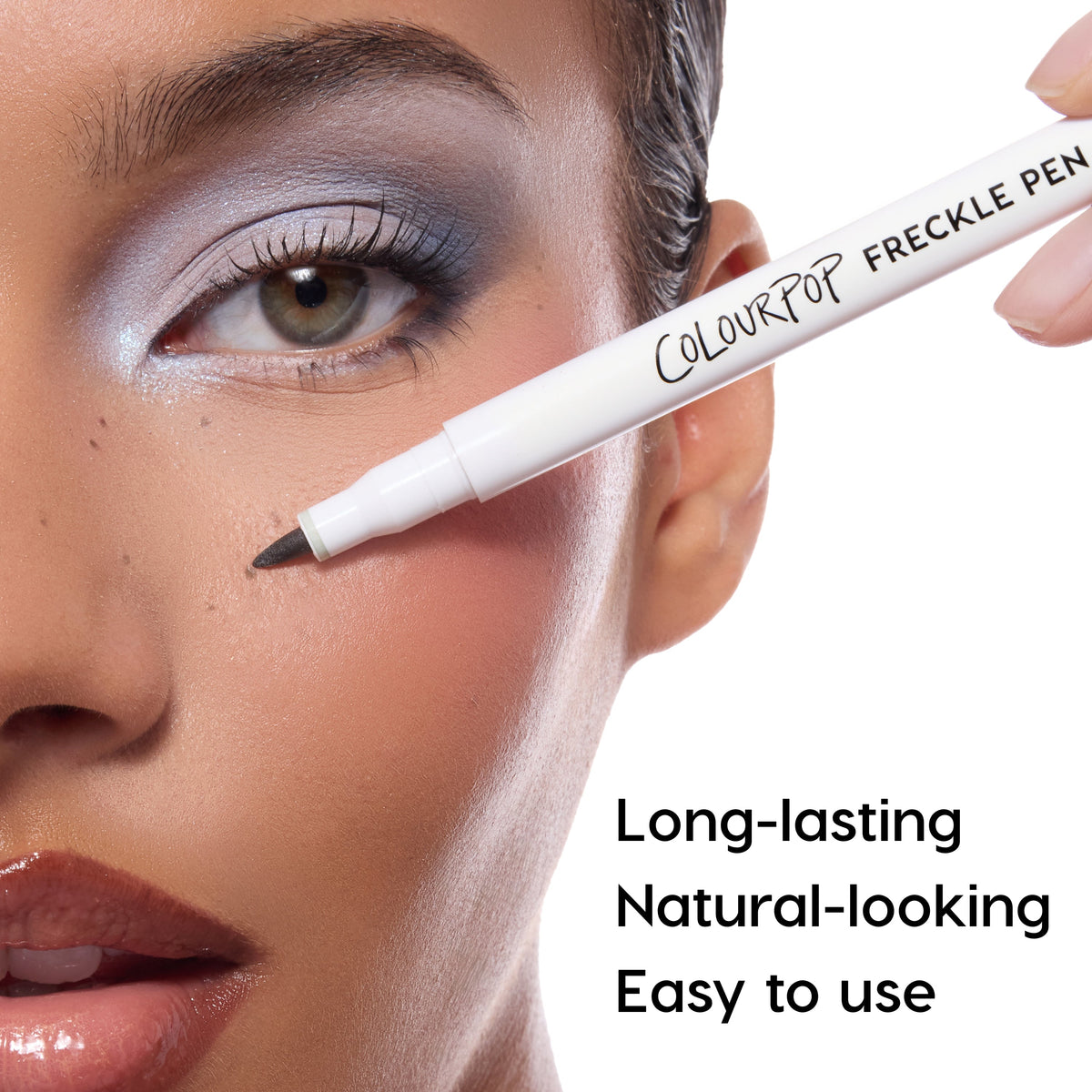 Close-up of a person applying a ColourPop freckle pen to their face with text highlighting features.