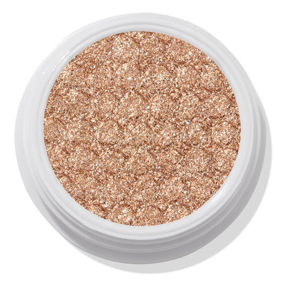 A Little Quarky Super Shock Shadow by ColourPop - sparkly warm champagne–rose gold pigment - fills a round white pot, shimmering with ultra-glitter texture in a close-up studio shot on a white background.
