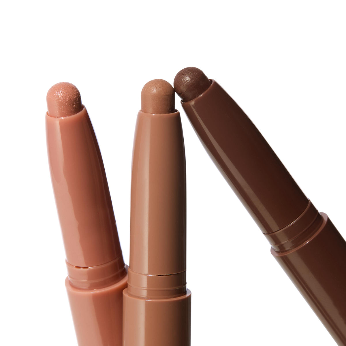 Matte Nudes ColourPop Shadow Stix trio, three uncapped cream eyeshadow pencils fanned to display peach nude, soft taupe, and deep cocoa tips, shown close-up on a white background.
