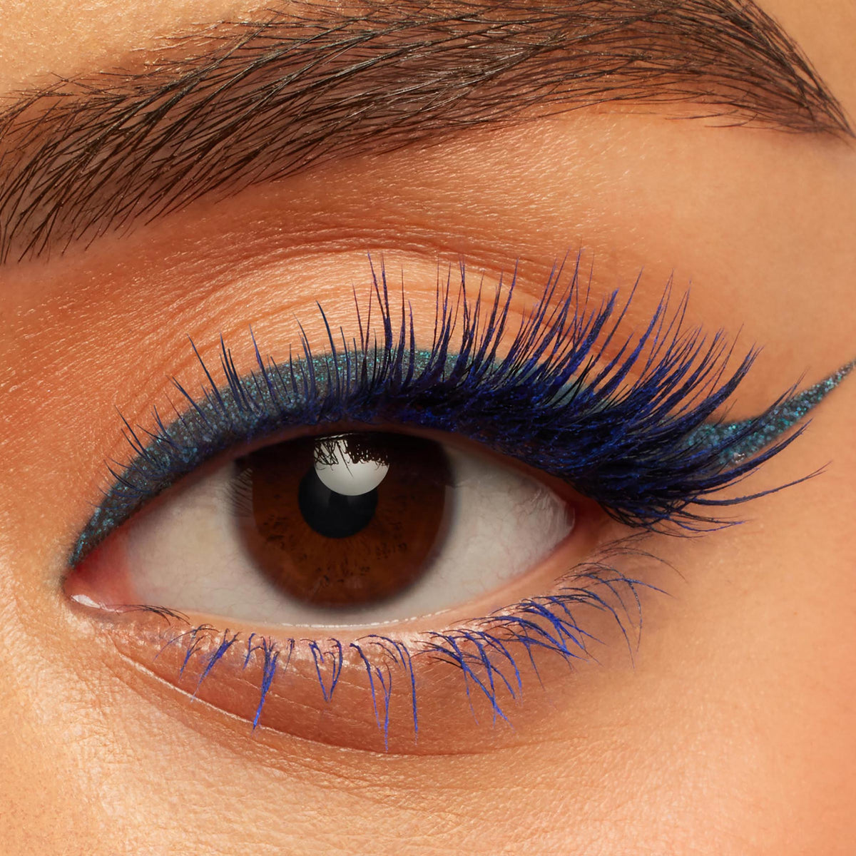 Winged metallic teal liner defining a brown eye, featuring Outer Space ColourPop Crème Gel Liner tracing the upper lash line with a crisp flick, paired with vivid cobalt lashes for a bold, space-inspired beauty close-up.