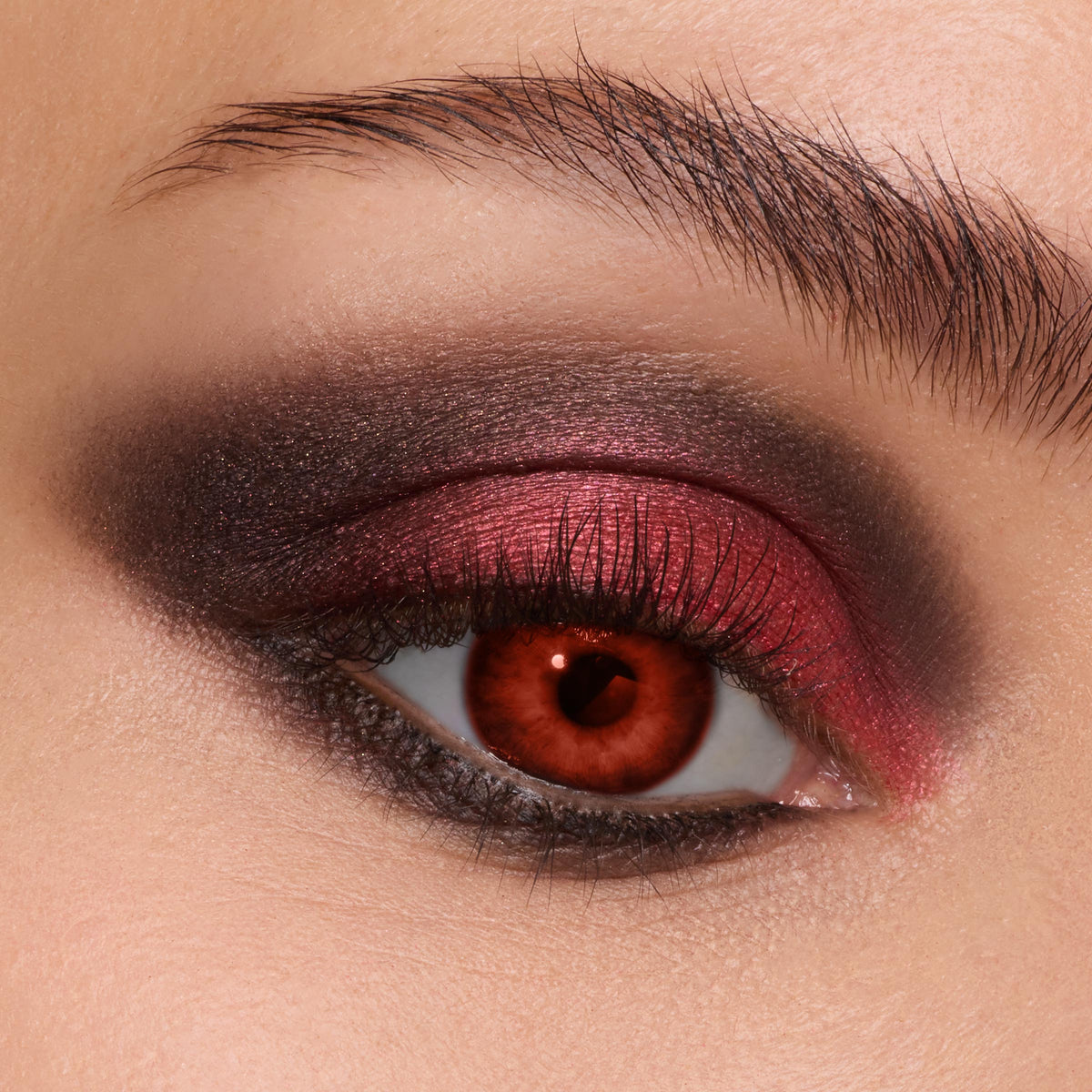 Smoky eye showcasing metallic cranberry-red shimmer blended with charcoal-black, created using the New Moon Shadow Palette, a ColourPop Shadow Palette, on a close-up eyelid with defined lashes and a groomed brow.