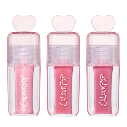 Three ColourPop Gloss Me Up ultra glossy lip set tubes from the Heart to Get collection standing upright, each in a clear pink case with heart-shaped cap and varying pink gloss shades on a clean white background.