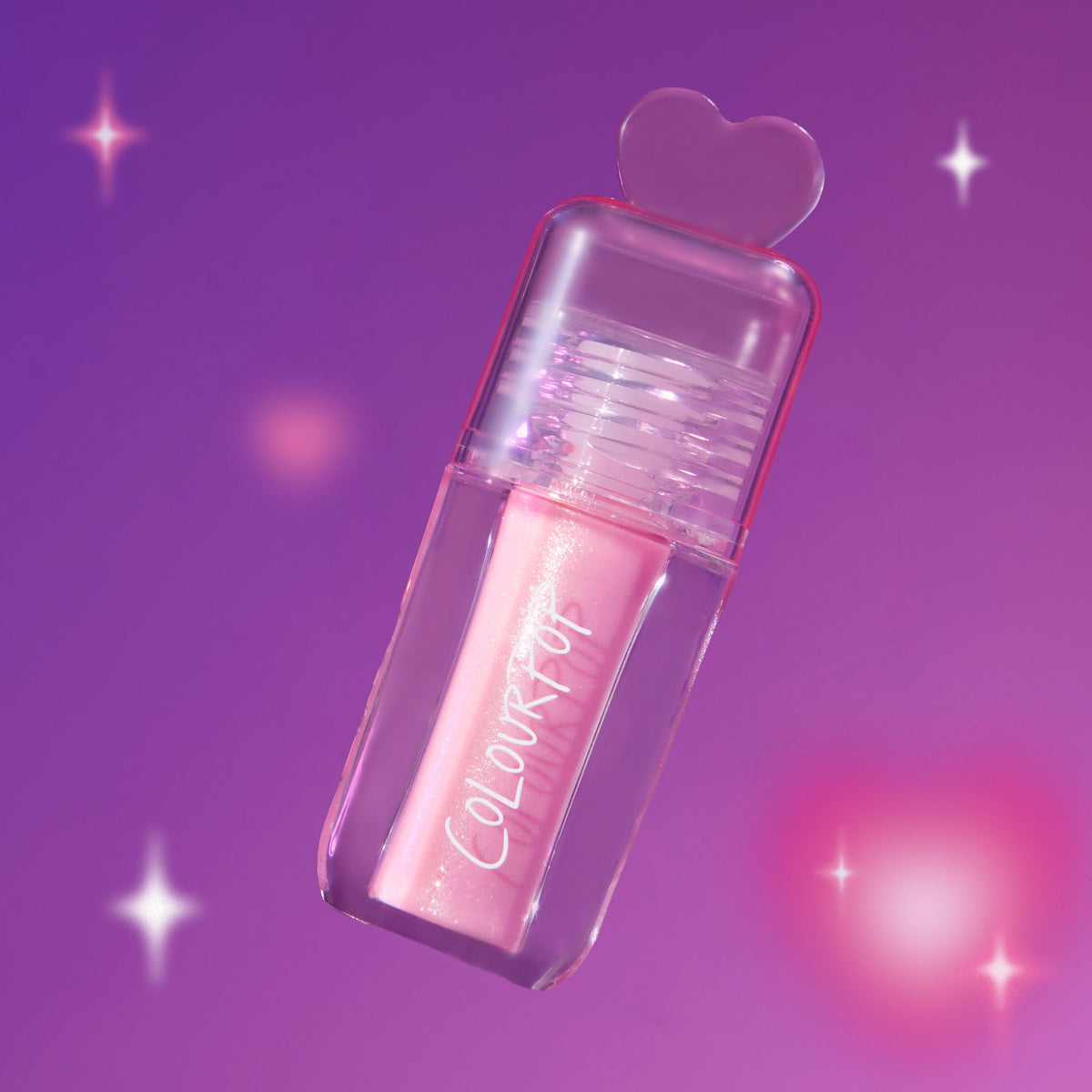ColourPop 2 Die 4 Ultra Glossy Lip in a clear tube with pink shimmer gloss and heart-shaped cap floating against a dreamy purple Heart to Get themed background with soft sparkles.