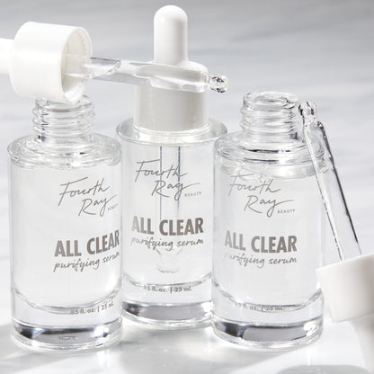 Fourth Ray Beauty All Clear Purifying Serum, a ColourPop Face Serum, three clear 0.85 fl oz (25 mL) glass dropper bottles with pipettes releasing transparent drops on a bright white surface.