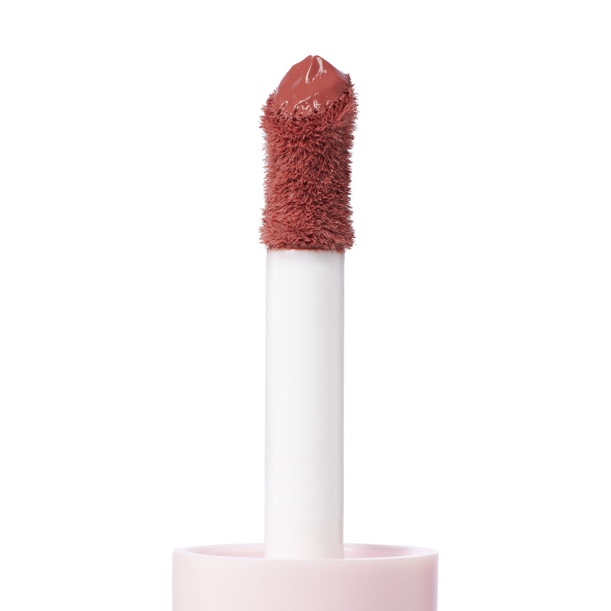 Doe-foot applicator coated in the creamy rosy-nude Culver City shade of ColourPop Liquid Blush, shown in macro close-up with a plush flocked tip rising from a soft pink tube against a clean white background.