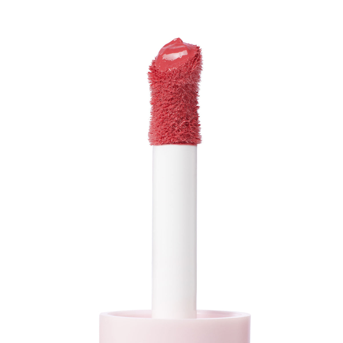 Doe-foot applicator coated in the warm pink She’s Cute shade from ColourPop Liquid Blush, lifting creamy pigment with a plush, fuzzy tip; close-up product macro on a white background highlighting texture and glossy finish.