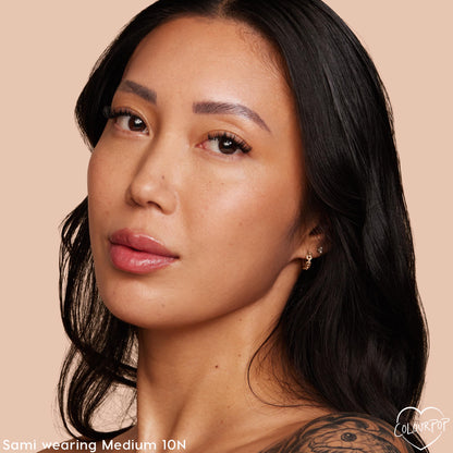 Model wearing Medium 10 N, showcasing a natural, dewy finish from ColourPop Pretty Fresh Tinted Moisturizer; close-up face with a neutral undertone against a soft peach background, minimal makeup for everyday wear.