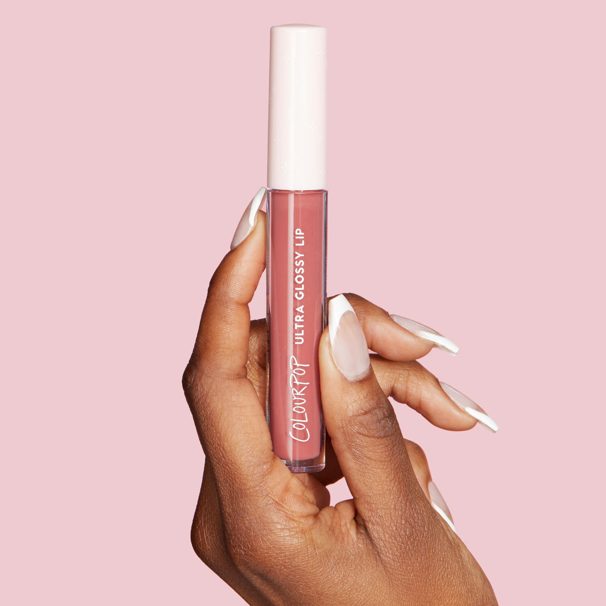 ColourPop Ultra Glossy Lip in Pasadena, a rosy mauve gloss, held between manicured fingers; clear tube with pale pink cap and white logo shown against a soft pink background.