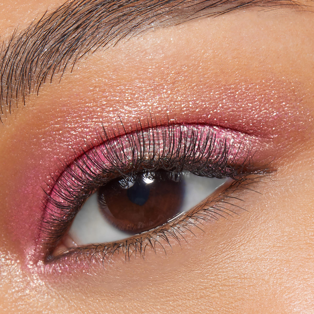 ColourPop Roy G. Biv Super Shock Shadow sweeps a metallic pink shimmer across a brown eye, showing smooth payoff and fine sparkle on the lid, with defined lashes and a clean brow in a close-up beauty swatch.
