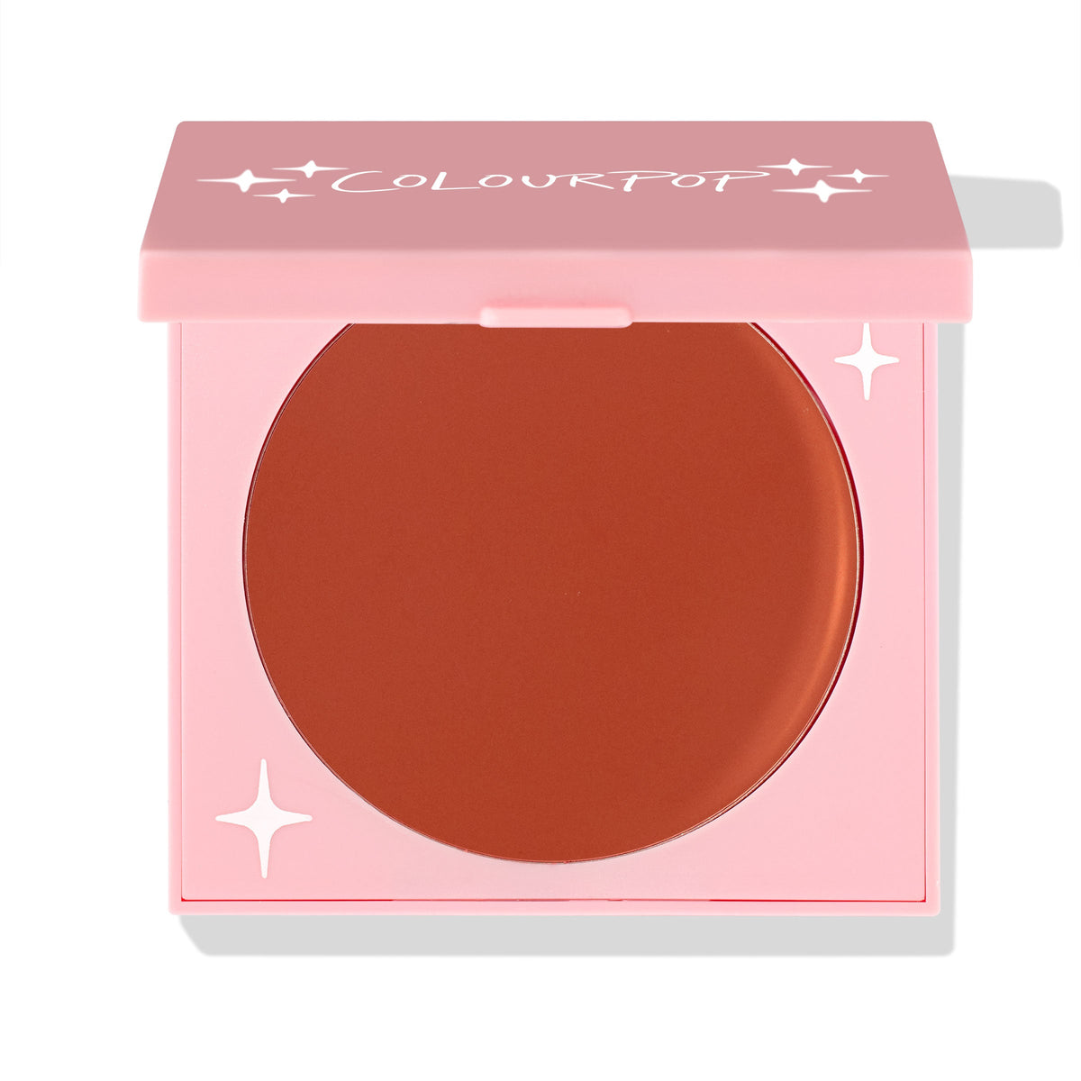 ColourPop Cream Blush Sunset Strip rests in a half-closed pink square compact, exposing a smooth warm terracotta pan with white star accents, studio product shot on a white background.