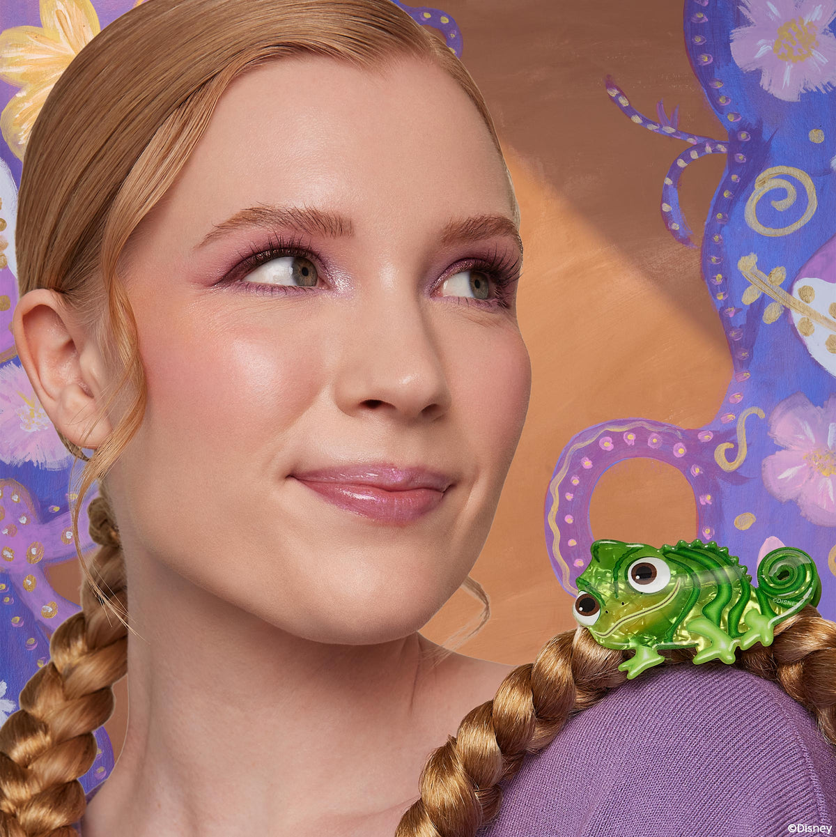 ColourPop Tangled Pascal Hair Clip secures a blonde braid, the glossy green chameleon barrette perched near the shoulder on a model in a lavender top, set against a whimsical purple-and-gold floral Rapunzel-inspired backdrop; hair accessory.