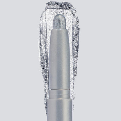 ColourPop Shadow Stix in Witch, Please showcases a creamy icy-silver shimmer, the crayon tip extended with a bold swatch behind to highlight pigment and sparkle, centered in a sleek silver tube on a light gray background.