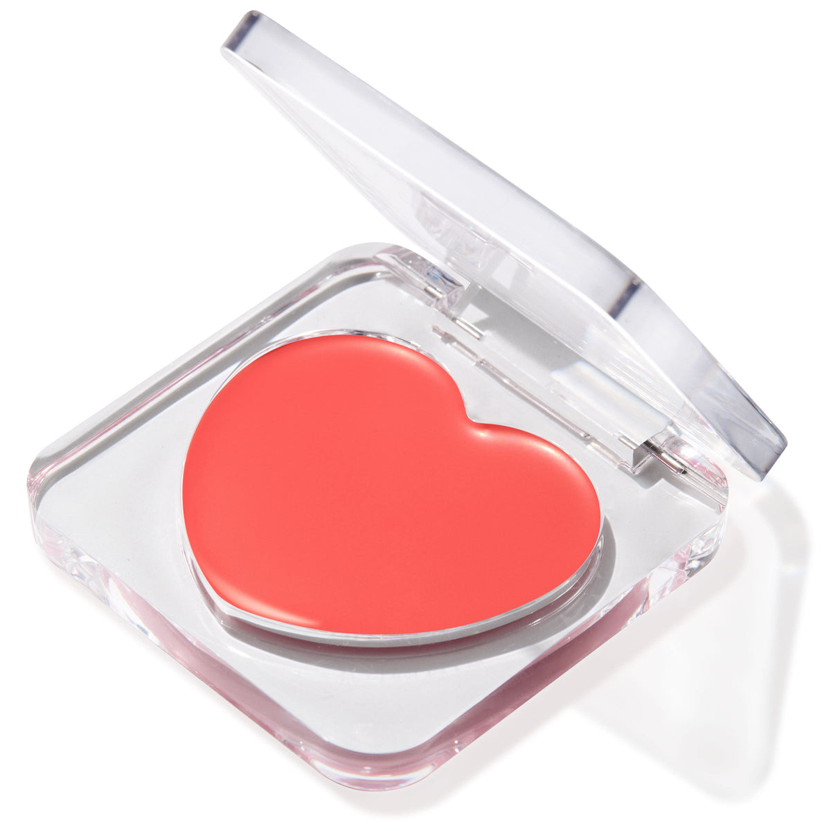 Heart-shaped coral pink Baby Bunny balm sitting in a half-open clear acrylic compact on a white background, a creamy multipurpose ColourPop Lip and Cheek Balm for dewy color on lips and cheeks.
