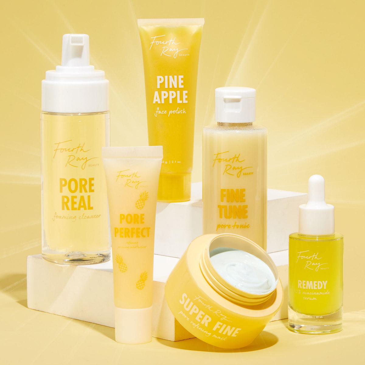 Pore Real Cleanser foaming face cleanser by ColourPop Fourth Ray Beauty stands center-left with a white pump, displayed beside Pineapple Face Polish, Fine Tune pore tonic, Super Fine mask, and Remedy serum on a bright yellow studio backdrop.