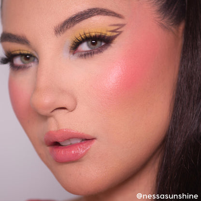 Model showcasing bold yellow eyeshadow with graphic black winged liner, fluttery lashes, rosy blush, and glossy pink lips, demonstrating the Pokémon x ColourPop Collection from the ColourPop Full Collection Set in a studio close-up.